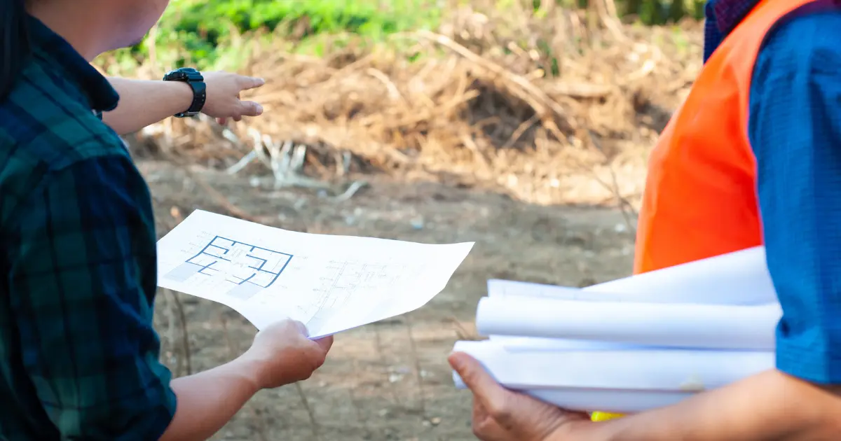 Technicians reviewing house plans on site before applying for the necessary permits to build a house