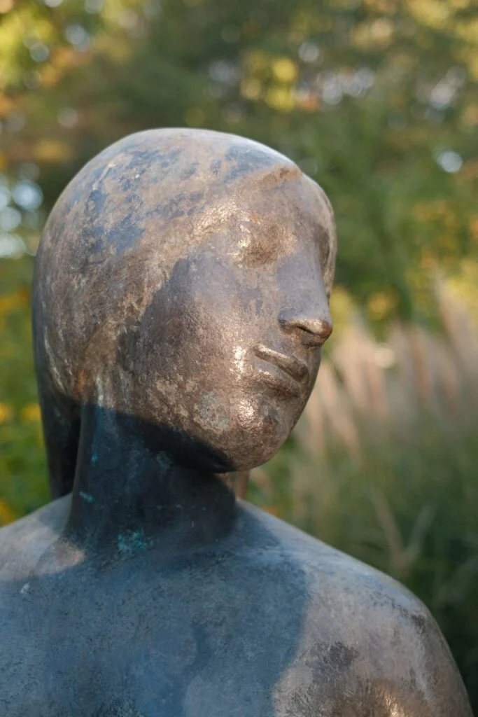 Busto de bronce en un jardín con luz de tarde
