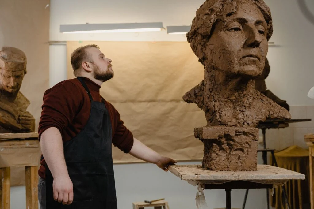 Emilio delante de un busto en barro recién modelado